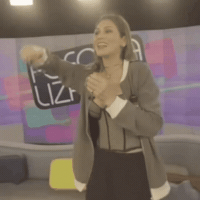 A Woman Singing Into A Microphone In Front Of A Fofo Sign GIF