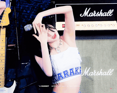 A Woman Singing Into A Microphone In Front Of A Marshall Amp GIF