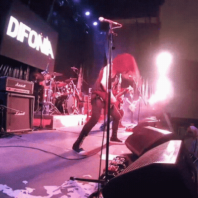 A Woman Singing Into A Microphone In Front Of A Sign That Says " Difona " GIF