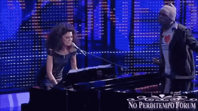 A Woman Singing Into A Microphone Next To A Man Playing A Piano With The Words No Perditempo Forum Written On The Bottom GIF