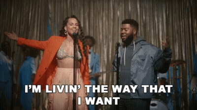 A Woman Singing Into A Microphone Next To A Man Who Says I 'M Livin GIF