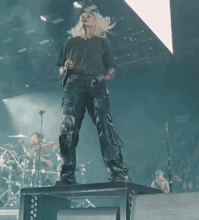 A Woman Singing Into A Microphone On Stage GIF