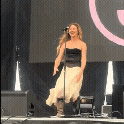 A Woman Singing Into A Microphone While Dancing On Stage GIF