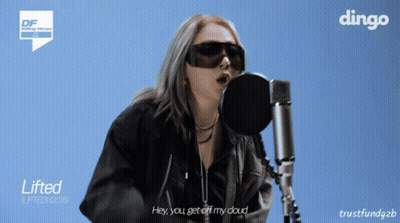 A Woman Singing Into A Microphone With A Dingo Logo On The Bottom GIF