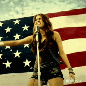 Woman Singing Into Microphone Behind American Flag GIF