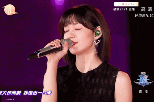 A Woman Singing Into A Microphone With Chinese Writing On The Bottom GIF