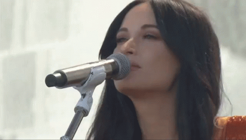 A Woman Singing Into A Microphone With Her Eyes Closed . GIF