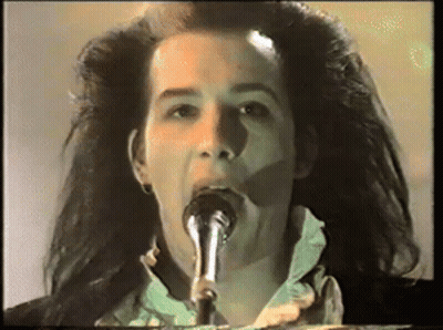 A Woman Singing Into A Microphone With Her Mouth Open GIF