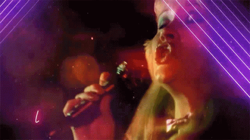 A Woman Singing Into A Microphone With The Letter L Visible GIF