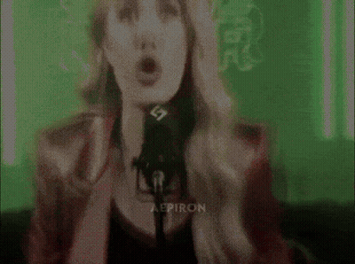 A Woman Singing Into A Microphone With The Letters Aep On Her Chest GIF