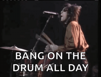 A Woman Singing Into A Microphone With The Words Bang On The Drum All Day Written Below Her GIF