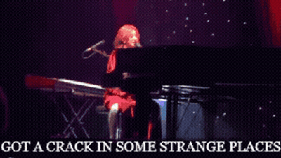 A Woman Singing Into A Microphone With The Words Got A Crack In Some Strange Places Below Her GIF