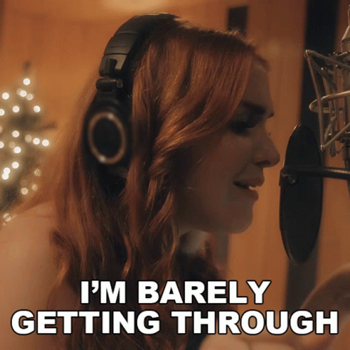 A Woman Singing Into A Microphone With The Words I 'M Barely Getting Through Behind Her GIF