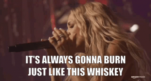 A Woman Singing Into A Microphone With The Words It 'S Always Gonna Burn Just Like This Whiskey Below Her GIF