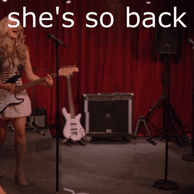 A Woman Singing Into A Microphone With The Words She 'S So Back GIF