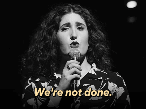 A Woman Singing Into A Microphone With The Words " We 'Re Not Done " On The Bottom GIF