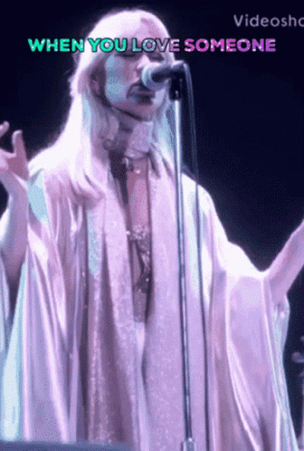 A Woman Singing Into A Microphone With The Words When You Love Someone Behind Her GIF