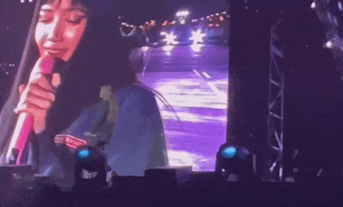 A Woman Singing Into A Pink Microphone On Stage GIF