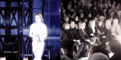 A Woman Singing On Stage Next To A Group Of People GIF