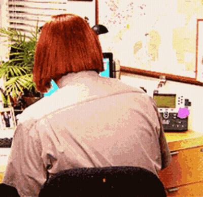 A Woman Sits At A Desk With A Telephone And A Map On The Wall Behind Her GIF