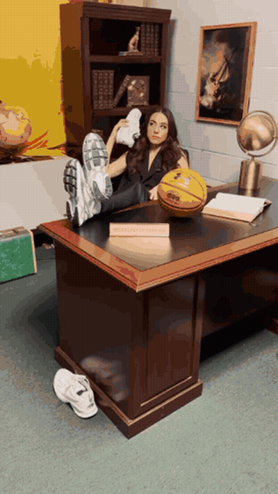 A Woman Sits At A Desk With Her Feet Up And A Basketball On The Desk With A Sign That Says Basketball Coach GIF