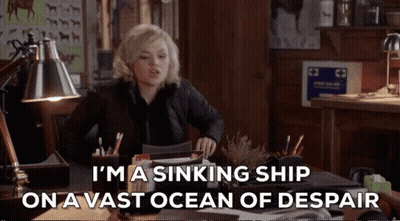 A Woman Sits At A Desk With The Words I 'M A Sinking Ship On A Vast Ocean Of Despair GIF