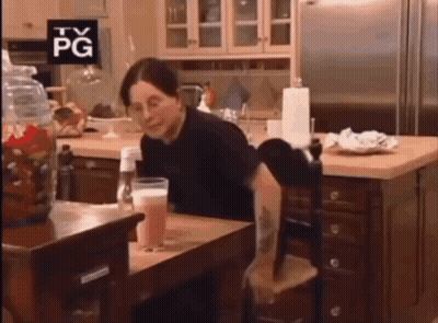 A Woman Sits At A Table With A Tv Pg Sign Above Her Head GIF