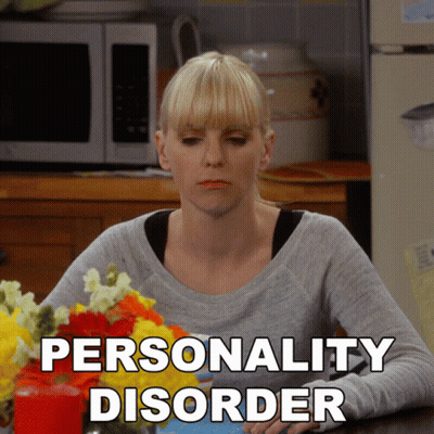 A Woman Sits At A Table With Flowers And The Words Personality Disorder Written On The Bottom GIF