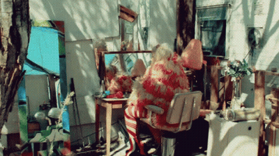 A Woman Sits In A Chair In Front Of A Mirror GIF