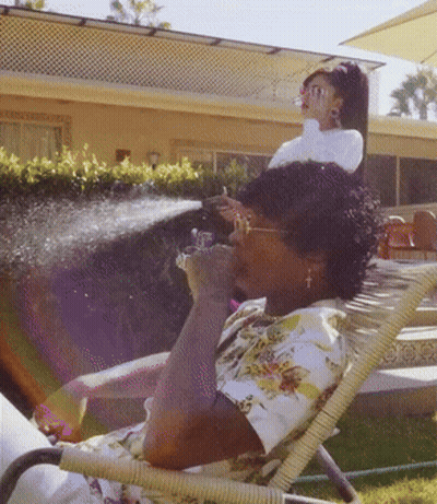 A Woman Sits In A Chair With A Hose Spraying Her Face GIF