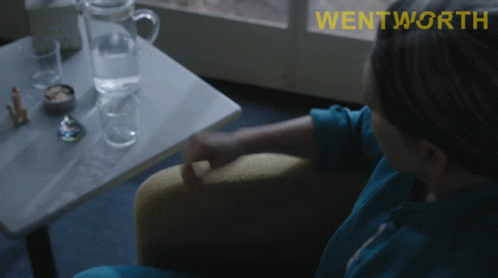 A Woman Sits In A Chair With The Word Wentworth On The Bottom Right GIF