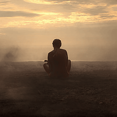 A Woman Sits In A Lotus Position In Front Of A Sunset Sky GIF