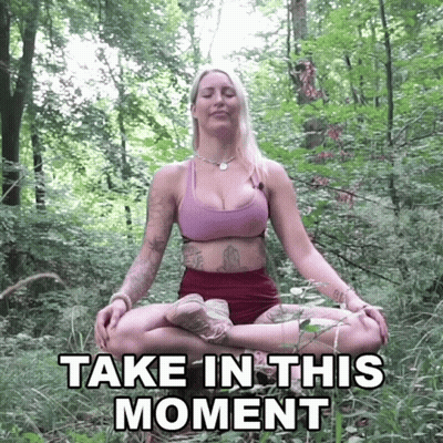 A Woman Sits In A Lotus Position In The Woods With The Words Take In This Moment Written Below Her GIF