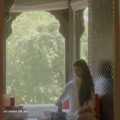 A Woman Sits In Front Of A Window With A Candle GIF