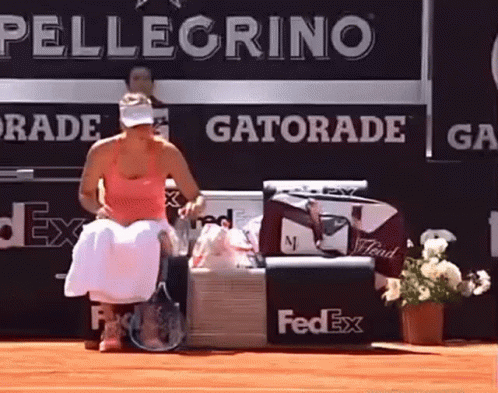 A Woman Sits On A Bench In Front Of A Gatorade Advertisement GIF