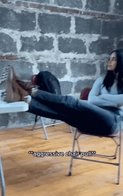 A Woman Sits On A Chair With Her Feet Up And The Words " Aggressive Chair Pull " Above Her GIF
