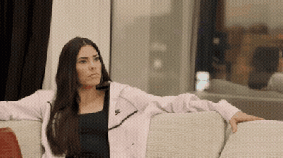 A Woman Sits On A Couch Wearing A Nike Jacket GIF