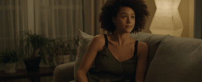 A Woman Sits On A Couch With A Glass Of Wine In Her Hand GIF