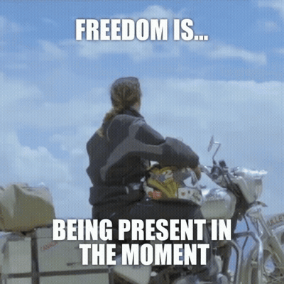 A Woman Sits On A Motorcycle With The Words " Freedom Is Being Present In The Moment " GIF