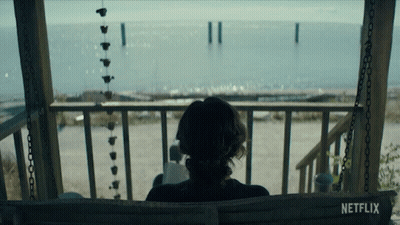 A Woman Sits On A Porch Swing With A Netflix Logo Visible GIF