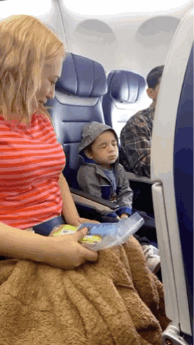 A Woman Sits On An Airplane Next To A Little Boy Who Is Sleeping GIF