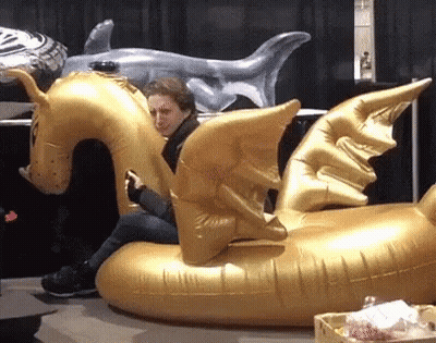 A Woman Sits On An Inflatable Dragon Float GIF