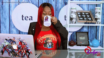 A Woman Sitting At A Desk Drinking From A Mug That Says Tea On It GIF