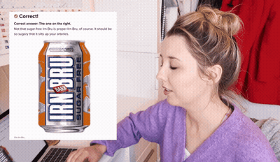 A Woman Sitting At A Desk With A Can Of Iron Bru In Front Of Her GIF