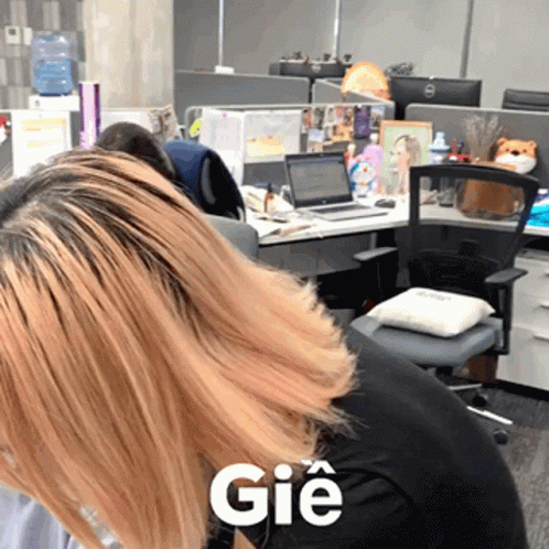 A Woman Sitting At A Desk With The Word Gie On Her Shirt GIF