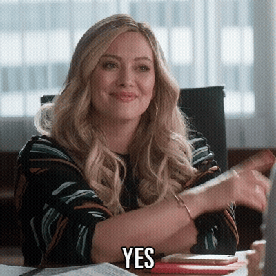 A Woman Sitting At A Desk With The Word Yes On Her Chest GIF