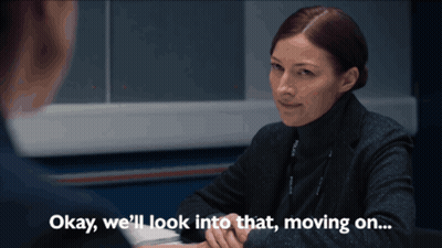 A Woman Sitting At A Desk With The Words " Okay We 'Ll Look Into That Moving On " GIF