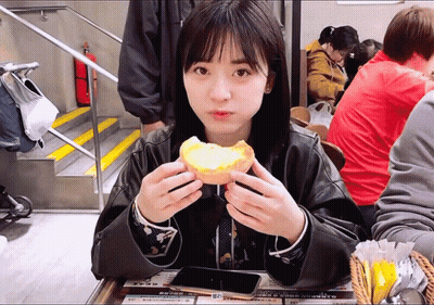 A Woman Sitting At A Table Eating A Sandwich With A Sign That Says ' A ' On It GIF