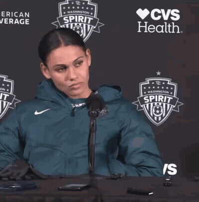 A Woman Sitting At A Table In Front Of A Cvs Health Sign GIF