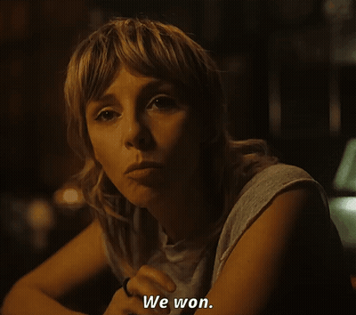A Woman Sitting At A Table Says " We Won " In A Dark Room GIF
